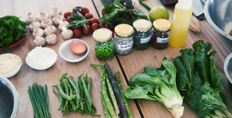 veggies and herbs laid out on a table next to a salad bowl