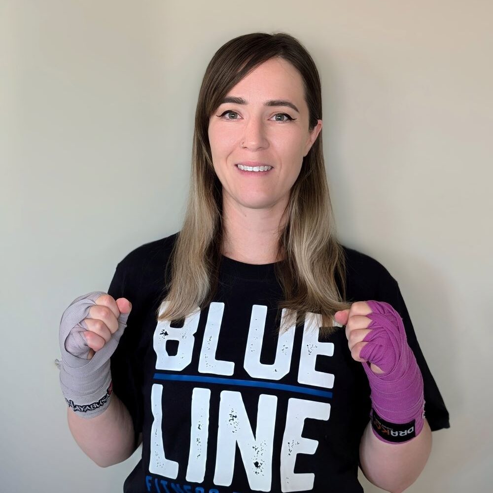 blueline fitness testing instructor jessica stands against a wall with boxing wraps on